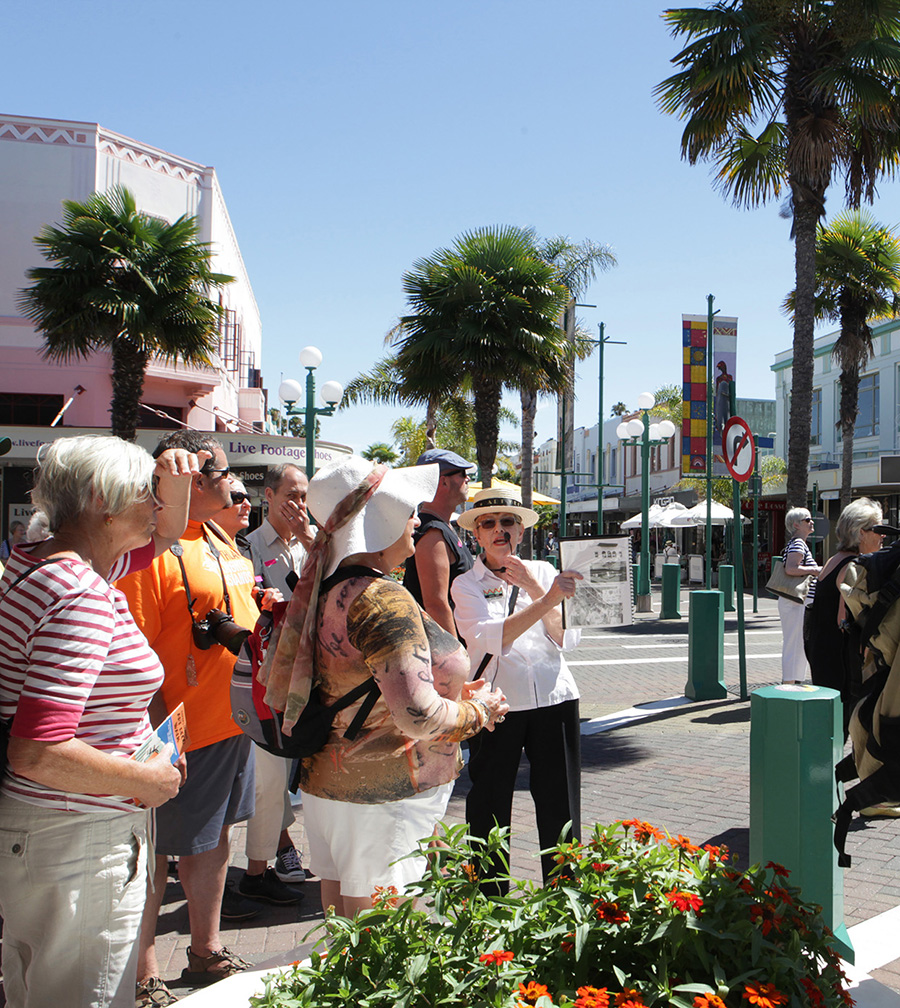 A group of tourists is led by a woman with a microphone outside